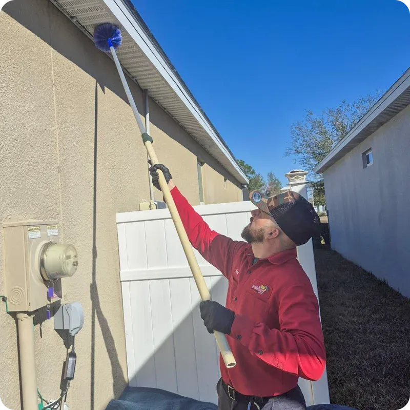 technician sweeping house eaves